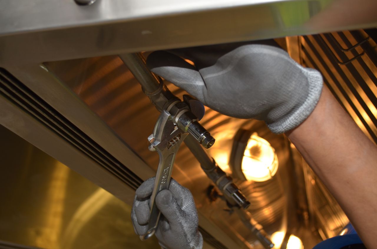 Tecnico che serra un raccordo su tubazioni metalliche con una chiave inglese